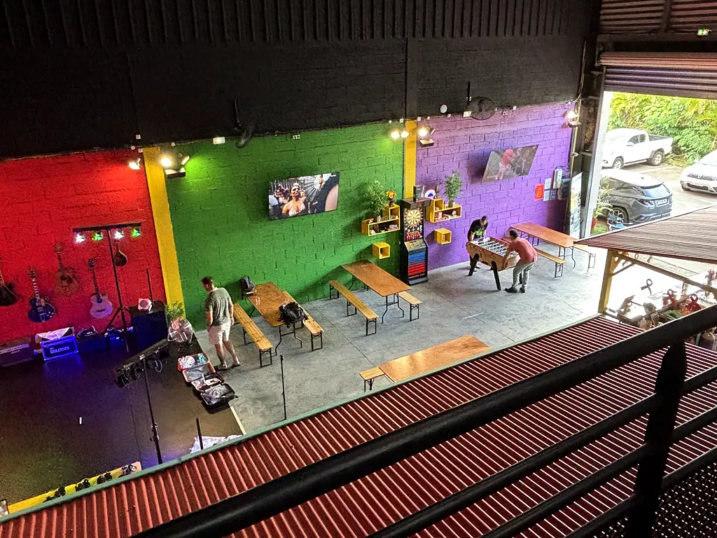 Le hangar vu de la mezzanine : la scène et ses guitares, les murs vert et violet, les fléchettes et le babyfoot.